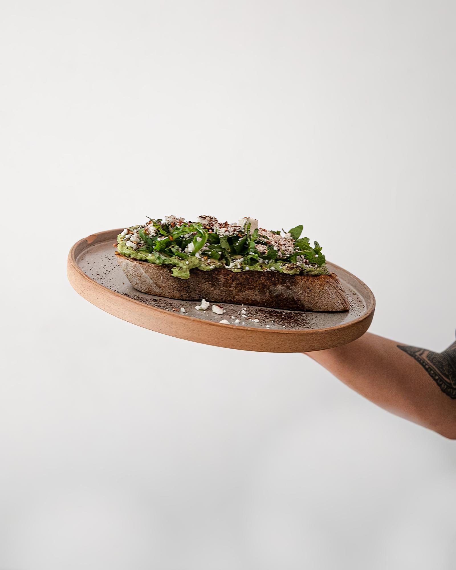 Chef demonstrating a plated dish on a wooden table